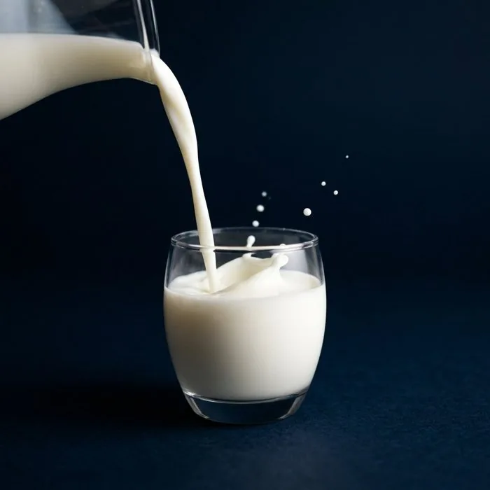 Milk poured into a glass on navy